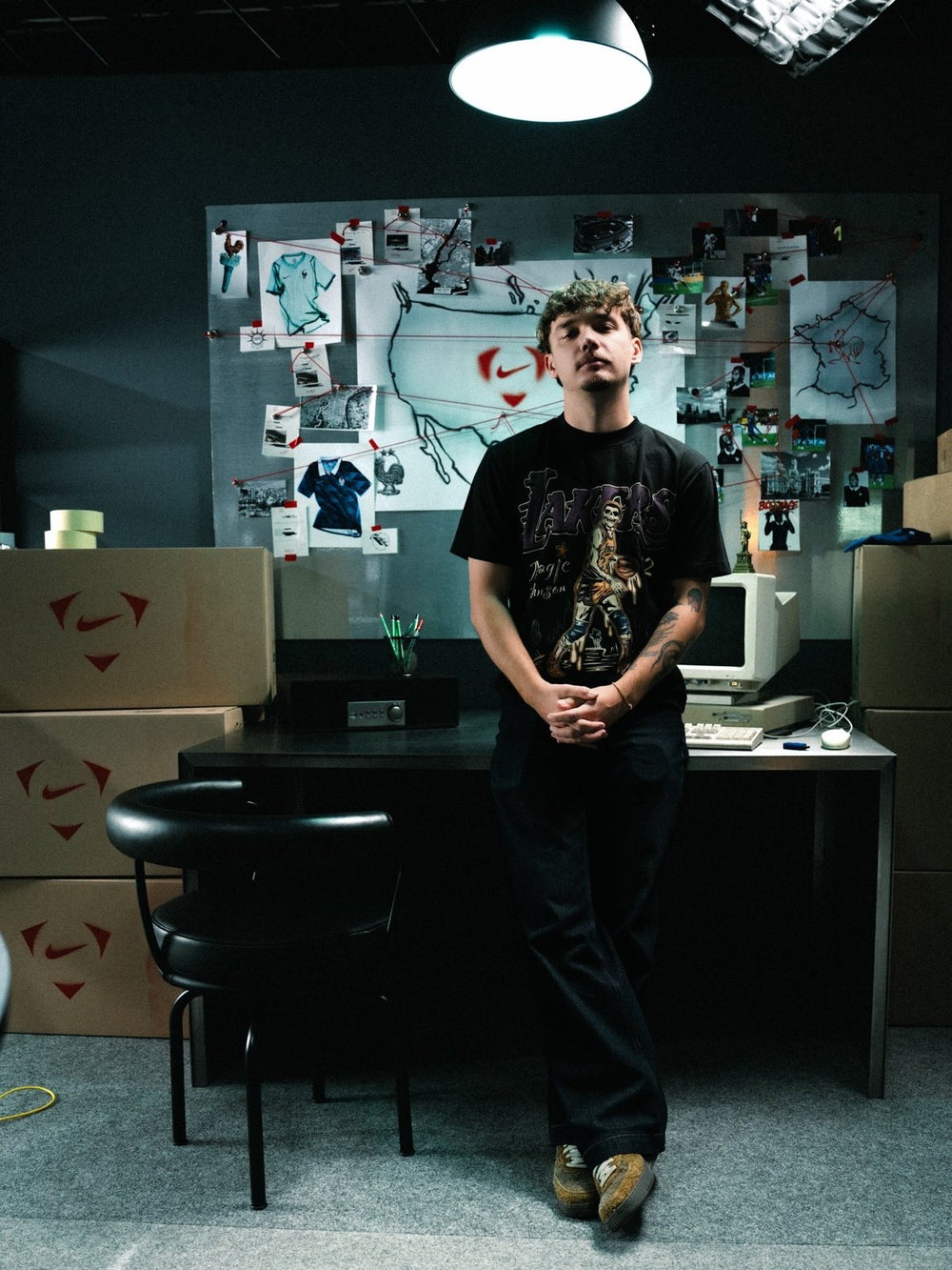 Daniel Evgrafov standing in a dark studio in front of a moodboard wall