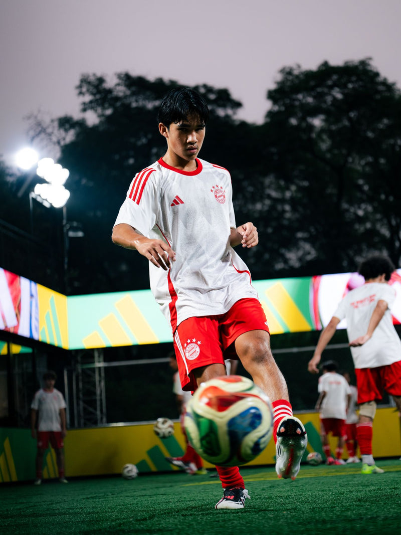 Young player controlling a ball on a floodlit pitch