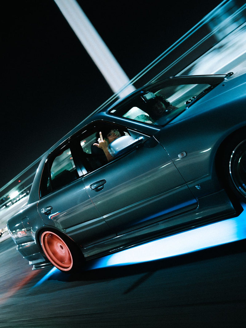 Panning shot of a car at speed at night, wheels blurred