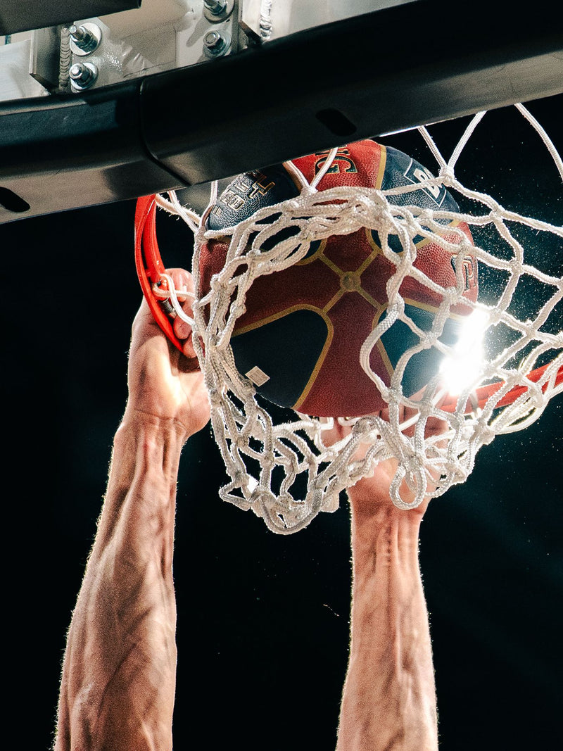 Basketball dropping through the net, hands still on the rim