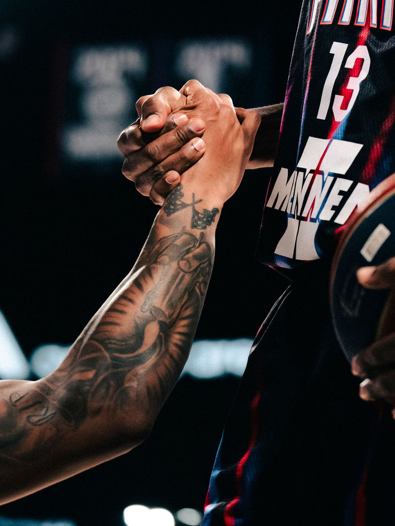 Two players clasping hands, tattooed forearms in close-up