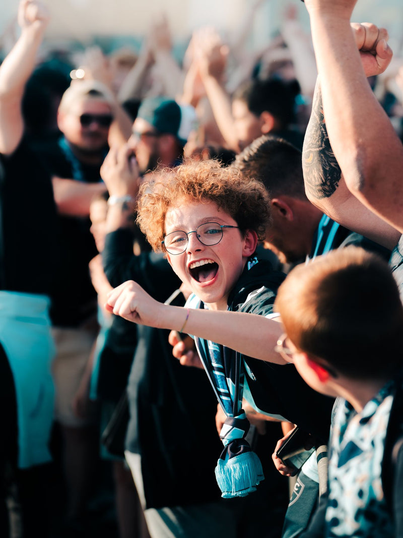 Young supporter celebrating with the crowd in a packed stand