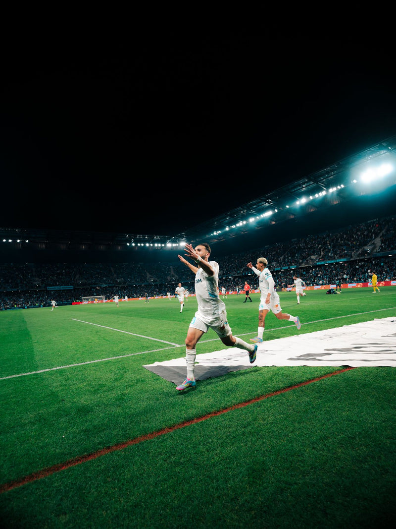Player striking the ball on a floodlit pitch at night