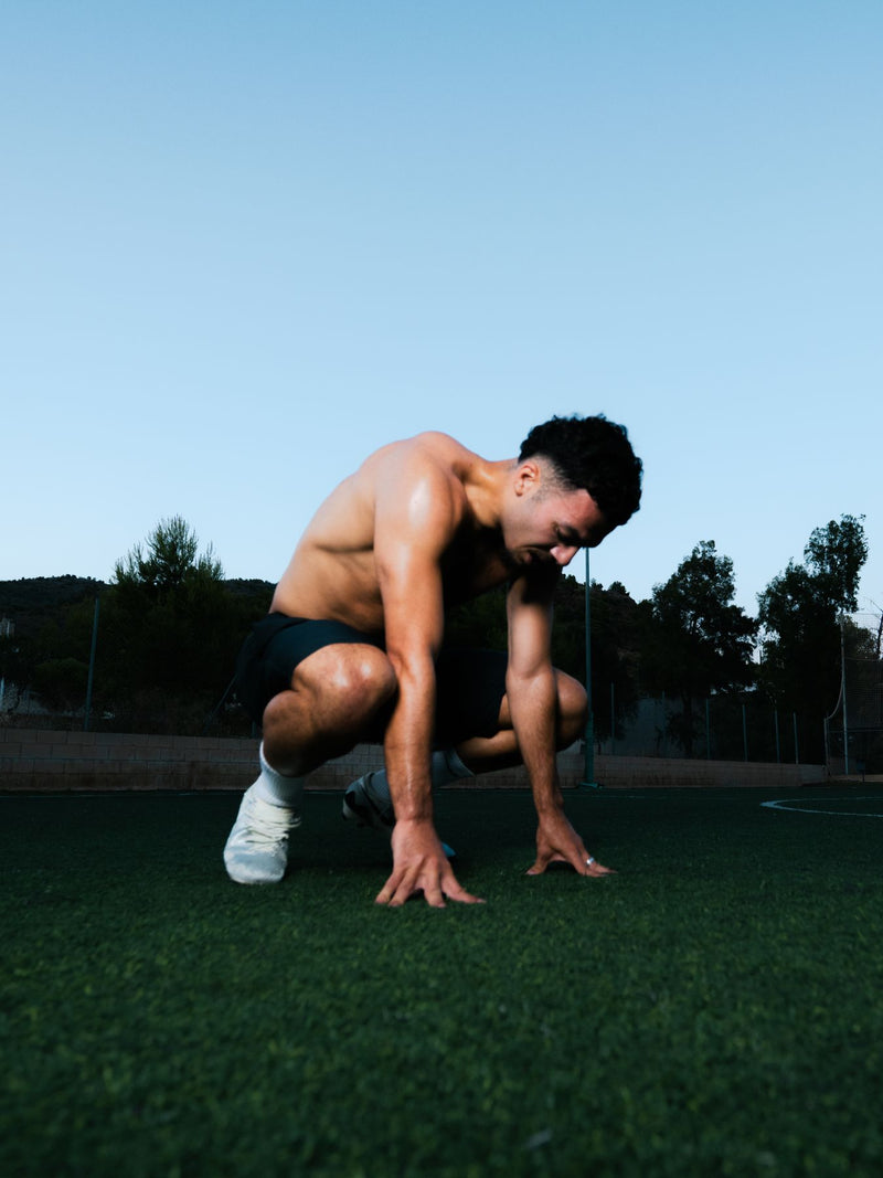 Shirtless player crouching on the grass at dusk