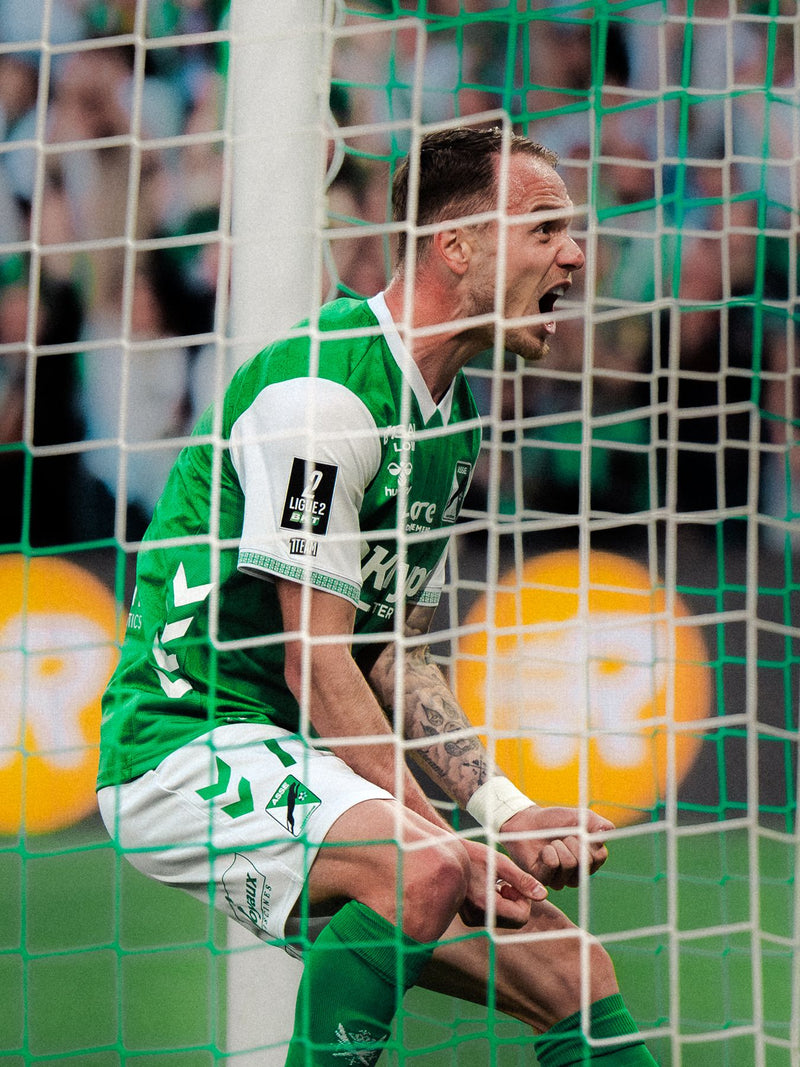 Player celebrating against the goal net after scoring