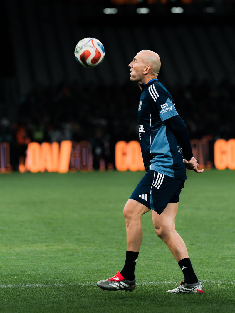 Player heading the ball in front of a stadium banner