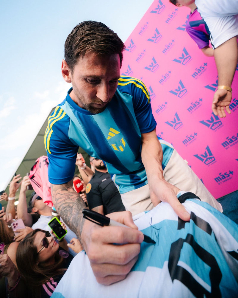 Footballer signing autographs for supporters at a barrier