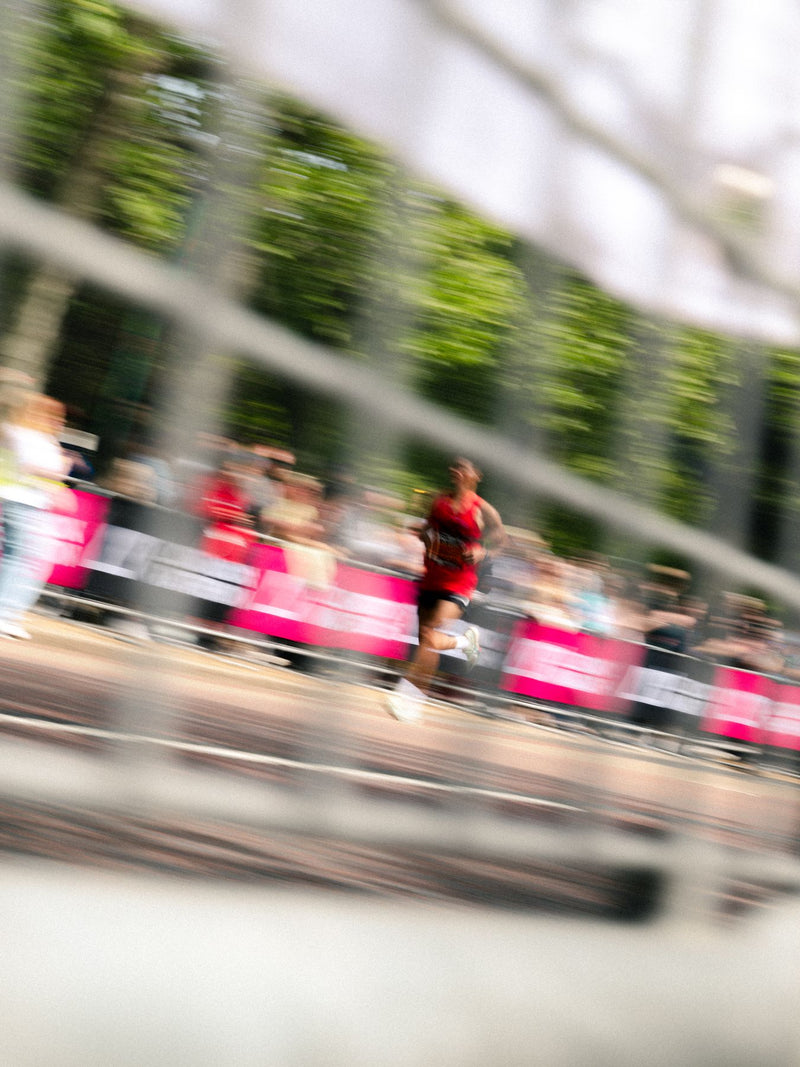 Runners blurred by a slow panning shot behind barriers