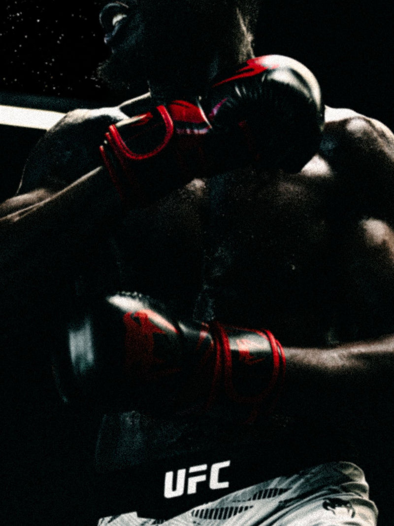 Two fighters exchanging punches in a dark cage, UFC branding behind