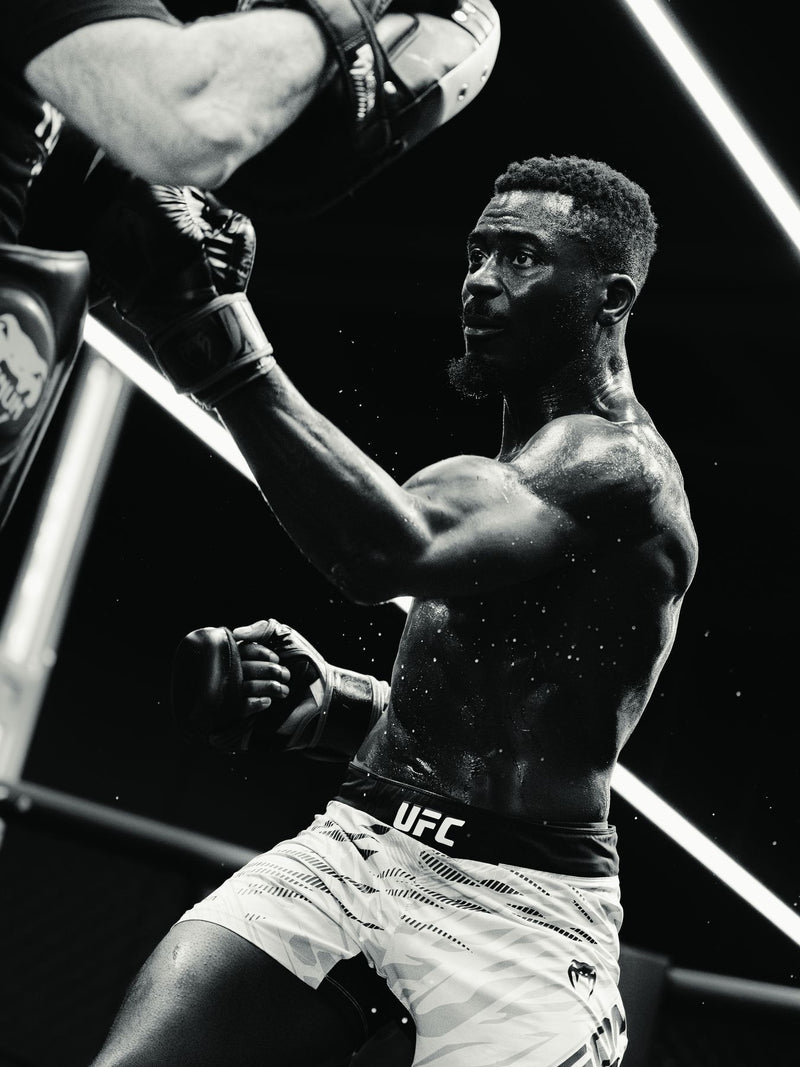 Black and white frame of a fighter throwing a punch in the octagon
