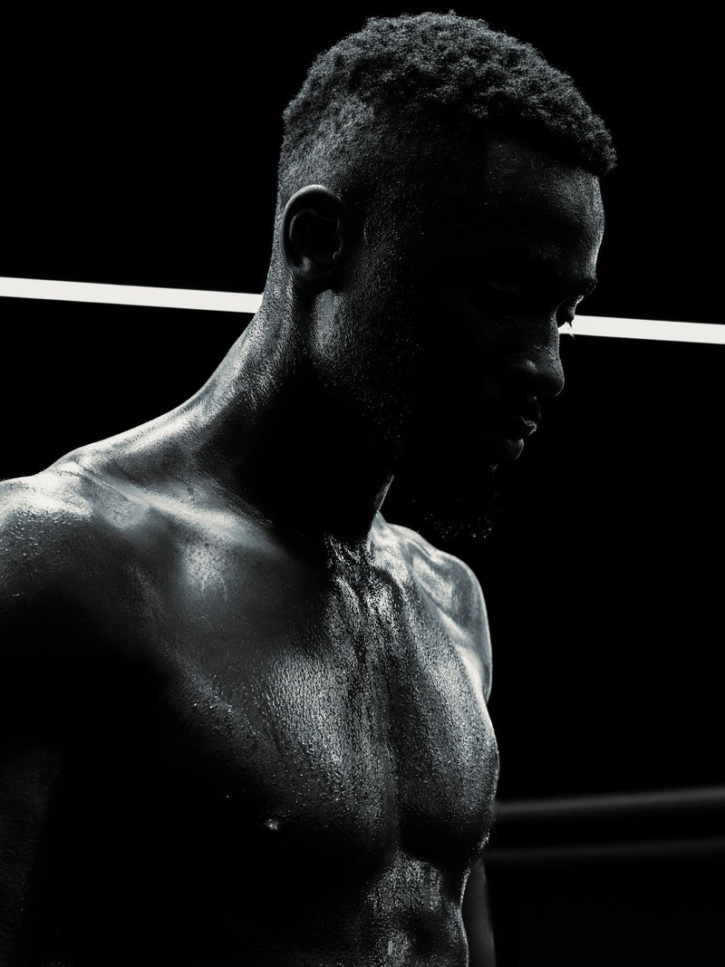 Backlit portrait of a boxer, torso and profile against black