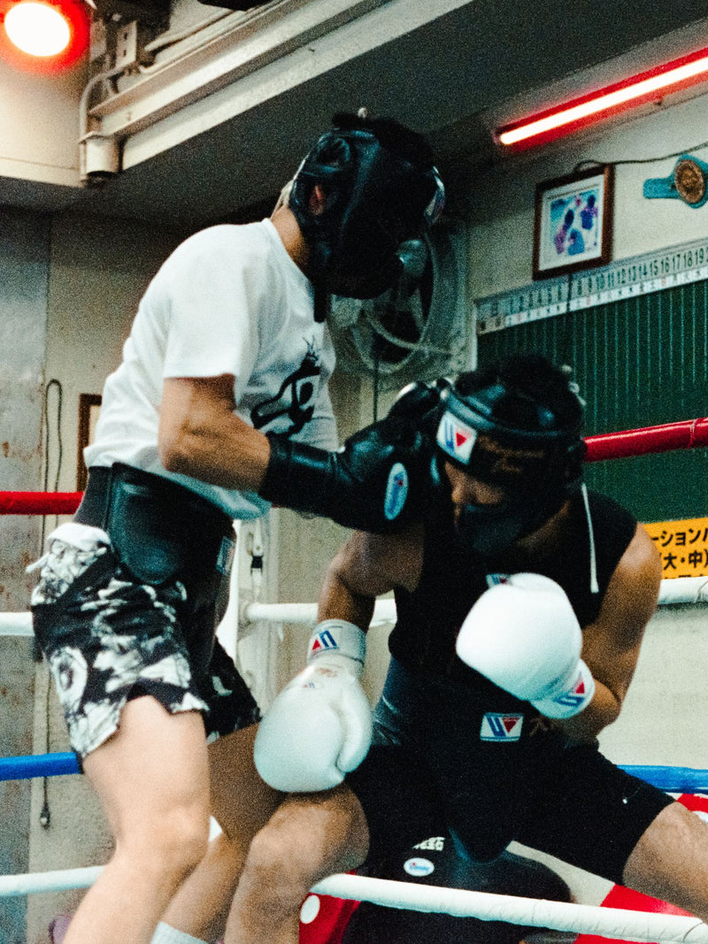Two boxers sparring in headgear in a Japanese gym