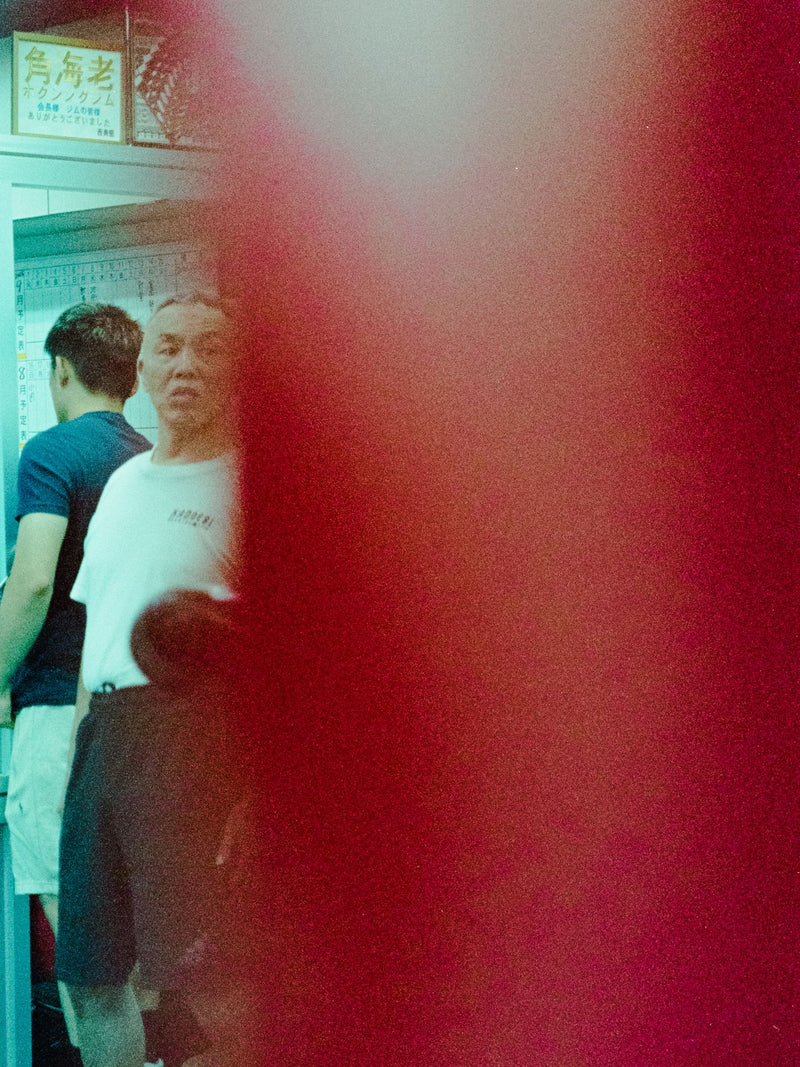 Boxers seen past a red heavy bag in a gym doorway