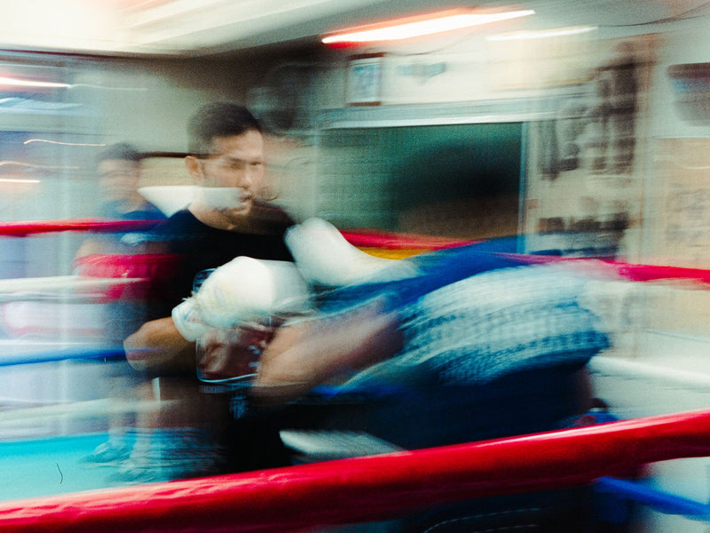 Blurred pan of a coach holding pads in the ring