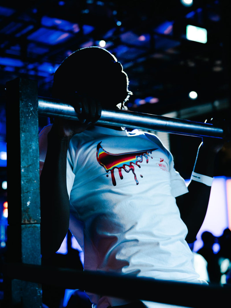 Athlete hanging from a bar in a printed Nike tee under blue light