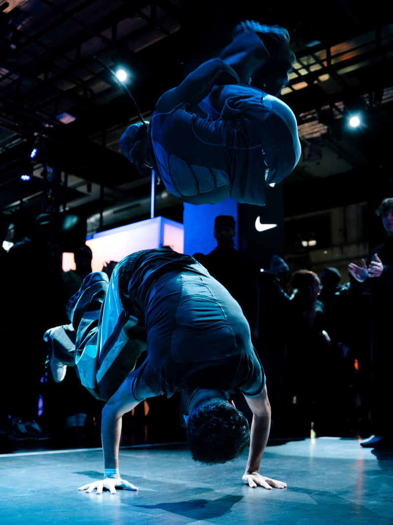 Two breakdancers, one mid-air, at a Nike event
