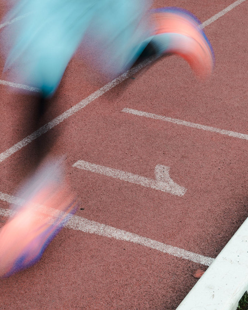 Motion-blurred runner legs on a red running track