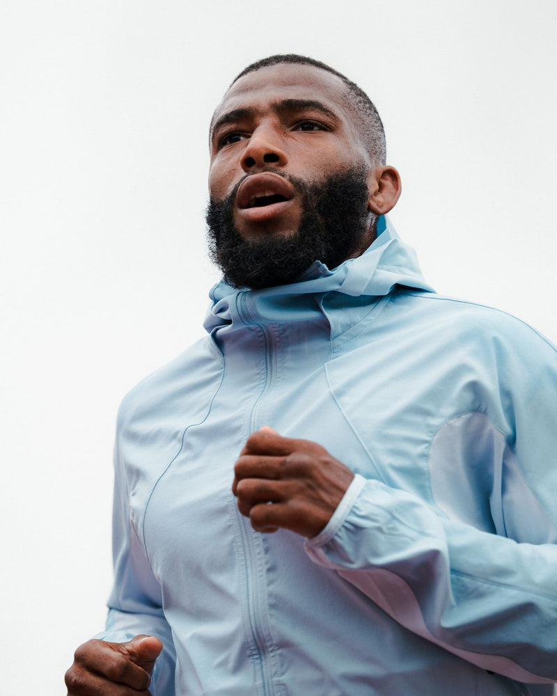 Low-angle portrait of a runner in a pale blue jacket