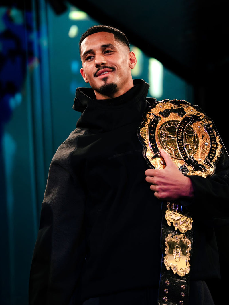 Athlete holding a championship belt under stage light